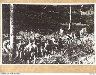 KOKODA TRAIL, NEW GUINEA. 1943-12-19. MEN OF THE 2/9 AUSTRALIAN INFANTRY BATTALION AND NATIVE CARRIERS ACTING AS EXTRAS DURING THE FILMING OF "RATS OF TOBRUK" BY CHAUVEL'S PRODUCTIONS