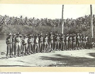 MILILAT, NEW GUINEA. 1944-06-19. PERSONNEL OF HEADQUARTERS, 5TH DIVISION STAND TO DURING THE MORNING PARADE. IDENTIFIED PERSONNEL ARE:- QX50988 STAFF SERGEANT L.C. THOMSON (1); QX49687 CORPORAL ..