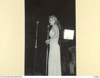 LAE, NEW GUINEA. 1944-07-24. CAROL LANDIS SINGING A SONG DURING A CONCERT FOR THE TROOPS STAGED BY THE JACK BENNY SHOW
