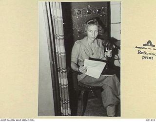 LAE, NEW GUINEA, 1945-05-07. PRIVATE G. HOOPER, WHO DID ALL THE BROADCASTING OF SHIP'S ORDERS, SEATED AT THE PUBLIC ADDRESS SYSTEM TABLE ABOARD THE MV DUNTROON. SHE IS ONE OF THE 342 AWAS EN ROUTE ..