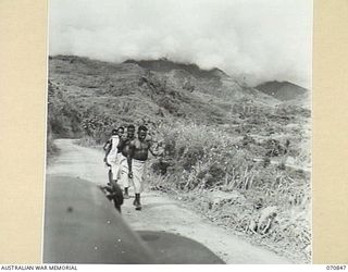 WAU - LAE ROAD, NEW GUINEA, 1944-02-20. APPROXIMATELY 4 MILES FROM WAU THE ROAD IS SHOWN WINDING AND RE-APPEARING TO THE RIGHT OF THE PICTURE. THE BULLDOG ROAD, ABOUT 5,500 FEET ABOVE SEA LEVEL, ..