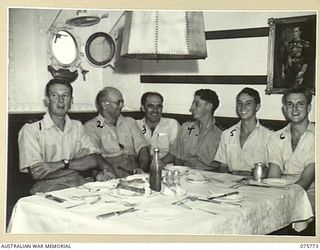 HOMBOLT BAY, NEW GUINEA. 1944-08/09. OFFICERS IN THE WARDROOM OF THE RAN CORVETTE, GEELONG. IDENTIFIED PERSONNEL ARE:- LIEUTENANT R.C. CRAN (1); ENGINEERING LIEUTENANT I.L. BARTON (2); LIEUTENANT ..