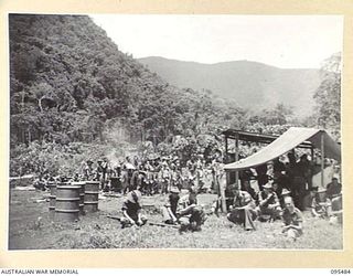 NANTAMBU, NEW BRITAIN, 1945-08-22. MEMBERS OF A COMPANY, 37/52ND INFANTRY BATTALION AT FINAL MESS PARADE IN THE STAGING AREA BEFORE EMPLANING. THE BATTALION WAS AIRLIFTED BY ROYAL NEW ZEALAND AIR ..
