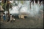 Cookery. Women and children standing outside dwelling