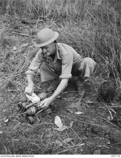 SOGERI VALLEY, NEW GUINEA. 1943-09-19. QX28237 SERGEANT WEEDON, INSTRUCTOR, 2/7TH AUSTRALIAN INDEPENDENT COMPANY, ATTACHED TO THE NEW GUINEA FORCE TRAINING SCHOOL, PREPARING TO DESTROY UNEXPLODED ..