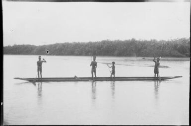 Four men standing up paddling a canoe, Ramu River, New Guinea, 1935 / Sarah Chinnery