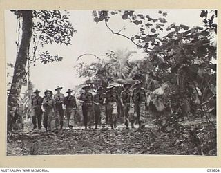 KARAWOP, NEW GUINEA. 1945-05-05. OFFICERS OF 2/1 INFANTRY BATTALION ENTERING BATTALION HEADQUARTERS ACROSS AN ANKLE DEEP LAKE OF MUD. IDENTIFIED PERSONNEL ARE:- MAJOR E.H. JACKSON-HOPE, OFFICER ..