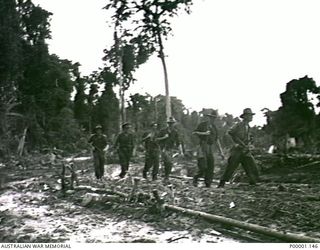 THE SOLOMON ISLANDS, 1945-05-02. AN AUSTRALIAN PATROL MOVING ALONG A MUDDY ROAD ON BOUGAINVILLE ISLAND. (RNZAF OFFICIAL PHOTOGRAPH.)