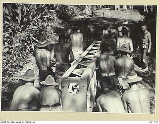 BOUGAINVILLE. 1945-04-18. 15 FIELD COMPANY ROYAL AUSTRALIAN ENGINEERS SAPPERS MANHANDLING STEEL HORN BEAMS FROM TRANSPORT TO ROLLERS DURING THE CONSTRUCTION OF A BRIDGE ACROSS DAWE CREEK. THE ..