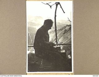 FINISTERRE RANGES, NEW GUINEA. 1944-01-23. QX37668 SERGEANT A.J. UFER, A COOK OF THE 2/9TH INFANTRY BATTALION, HAS NO TIME TO ADMIRE THE VIEW OF THE FARIA AND RAMU VALLEYS FROM HIS POSITION ON THE ..