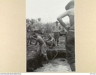 EVAPIA RIVER, NEW GUINEA, 1944-03-15. MEN OF THE 2/4TH FIELD COMPANY, ROYAL AUSTRALIAN ENGINEERS, PREPARING THE MAIN SUPPORT FOR A SUSPENSION BRIDGE CARRYING FOOT TRAFFIC AND FACILITATING DELIVERY ..