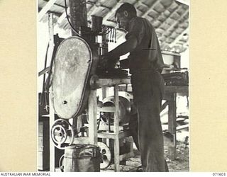 LABU POINT, LAE, NEW GUINEA. 1944-03-24. QX27843 SERGEANT G. T. PAGE, SETTING A PUMP FOR CALIBRATING ON A DIESEL TESTING, PHASING, AND CALIBRATING INJECTOR TESTER AT THE 1ST WATERCRAFT WORKSHOP