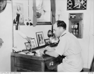 HOMBOLT BAY, NEW GUINEA. 1944-08/09. LIEUTENANT M.E. MATHERS, CAPTAIN OF THE RAN CORVETTE, GEELONG, WRITING A LETTER HOME IN HIS CABIN