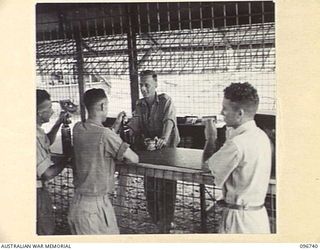 MOEM, WEWAK AREA, NEW GUINEA. 1945-09-17. BEER ISSUE DAY AT CANTEEN C PLATOON. CPL A.L. READ, 2/4 ARMOURED REGIMENT DETACHMENT WITH 4 INFANTRY TROOPS WORKSHOP, IS HANDING OUT THE BEER