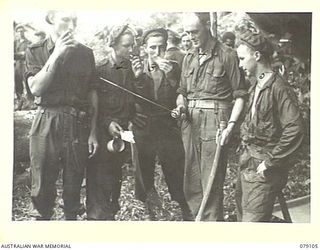 BOUGAINVILLE ISLAND. 1945-02-13. MEMBERS OF A COMPANY, 61ST INFANTRY BATTALION ADMIRING A JAPANESE SAMURAI SWORD HELD BY VX37706 WARRANT OFFICER II, H. ROBERTS, NEW GUINEA ADMINISTRATION UNIT (4). ..