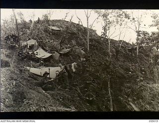 Faria Valley, New Guinea. 1943-10-17. The camp site of A Company, 2/16th Australian Infantry Battalion, AIF, on the hillside at John's Knoll, the most forward position at that time. The men shown ..