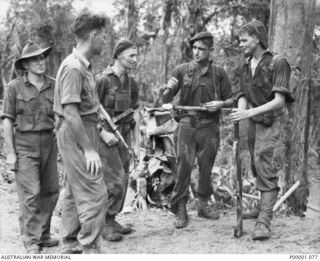 THE SOLOMON ISLANDS, 1945-03-27. COUNCIL OF WAR BETWEEN FRIENDLY FORCES ON THE NUMA NUMA TRAIL ON BOUGAINVILLE ISLAND. (RNZAF OFFICIAL PHOTOGRAPH.)