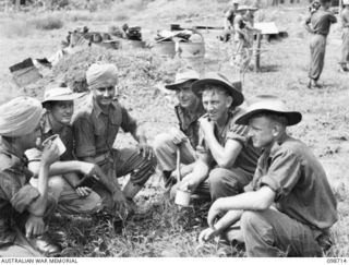 MISSION POINT, NEW GUINEA. 1945-11-09. PRIVATE CHIAN SINGH (1) AND PRIVATE JOGINDIA SINGH (3) MEMBERS OF THE INDIAN ARMY AND FORMER PRISONERS OF WAR, HAVING A CUP OF TEA WITH AUSTRALIAN SOLDIERS, ..