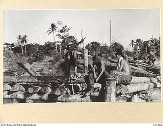 MADANG, NEW GUINEA. 1944-05-21. AUSTRALIAN TROOPS GRAPPLING FOR ABANDONED JAPANESE EQUIPMENT ALONGSIDE THE WHARF