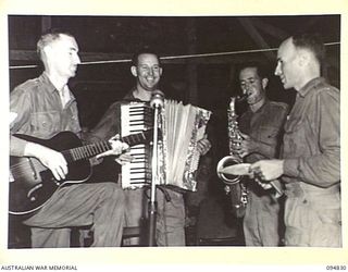 JACQUINOT BAY, NEW BRITAIN, 1945-08-07. A SECTION OF THE BAND SEEN DURING THE BROADCAST OF A RADIO PROGRAMME FROM HEADQUARTERS 11 DIVISION AMENITIES HUT. ARRANGED BY A HANDFUL OF MUSICIANS IT WAS A ..