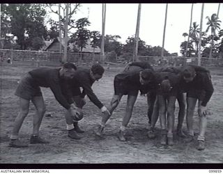 RABAUL, NEW BRITAIN, 1946-02-11. PRIVATE N. DAVIES, COACH, GIVING SCRUM DRILL TO MEMBERS OF 26TH INFANTRY BATTALION RUGBY LEAGUE TEAM. THE TEAM WON THE 11 INFANTRY BRIGADE PREMIERSHIP COMPETITION