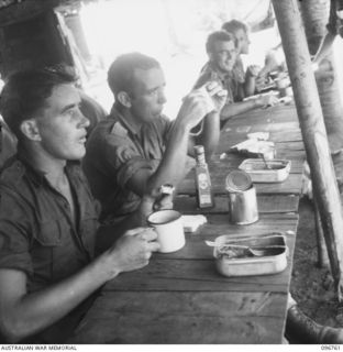 Trooper Frederick William John Randell (1) and Trooper G C Brookes (2), members of 2/6 Cavalry Commando Regiment Education Section, seated at the mess table