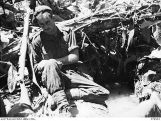 BOUGAINVILLE ISLAND, 1945-01-21. NX43081 PRIVATE W.T. RAE, 42ND INFANTRY BATTALION RESTING BESIDE HIS WATER-FILLED FOXHOLE AFTER AN ALL-NIGHT VIGIL AGAINST POSSIBLE JAPANESE INFILTRATION