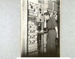 LAE, NEW GUINEA. 1944-04-03. WX2646 CORPORAL J.T. FLYNN (1), 19TH LINES OF COMMUNICATION SIGNALS, AT THE OPERATING BOARD OF THE TELEGRAPH CARRIER TERMINAL