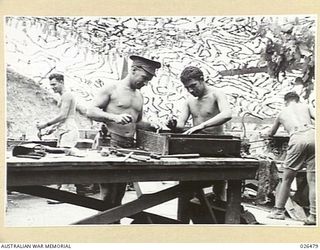 PORT MORESBY, PAPUA. 1942-08. WORKING UNDER A CAMOUFLAGE NET THESE MEN ARE CARRYING OUT REPAIRS AT AN AUSTRALIAN ORDNANCE WORKSHOP