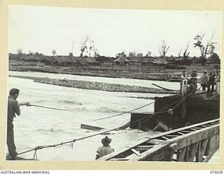 LAE, NEW GUINEA. 1944-08-09. PERSONNEL OF THE DESPATCH RIDER LETTER SERVICE HAULING MAIL ACROSS THE GAP IN THE BUTIBUM RIVER BRIDGE WHICH WAS WASHED AWAY DURING THE RECENT HEAVY FLOODS. TROOPS OF ..