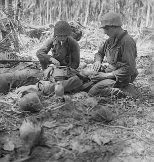 1942-12-28. PAPUA. TWO AMERICAN SOLDIERS DRESS THE WOUNDS OF AN AUSTRALIAN. THIS PHOTO WAS TAKEN DURING THE ACTUAL ADVANCE. (NEGATIVE BY G. SILK)