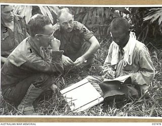 NADZAB, NEW GUINEA. 1943-09-20. UNITED STATES ARMY INTERPRETER, SERGEANT MUNEKAWA (FOREGROUND) INTERROGATING A CHINESE COOLIE, WHO HAD BEEN EMPLOYED BY THE JAPANESE, WHILE SERGEANT D.J. GRIMLEY ..