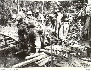 1943-01-26. PAPUA. NEARING THE END OF THE PAPUAN CAMPAIGN AGAINST JAPAN. EIGHT AUSTRALIANS PUSH A CAPTURED JAP TRAILER ACROSS AN IMPROVISED BRIDGE AT SANANANDA. USE OF THE TRAILER MADE EASIER THE ..