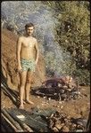 An unknown European man, standing in front of a cooking fire