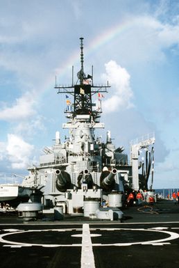 A rainbow provides the backdrop to the superstructure of the USS MISSOURI (BB-63) while the battleship is underway with other ships of its battle group during exercise RIMPAC '90 near Hawaii. Three of the vessel's Mark 7 16-inch/50-caliber guns can be seen in the foreground