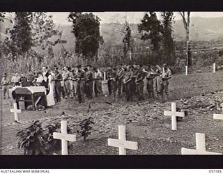 WAU, NEW GUINEA. 1943-08-29. VX117249 CHAPLAIN W. A. O'DRISCOLL, ROMAN CATHOLIC, OFFERING THE FIRST REQUIEM MASS FOR ALLIED TROOPS AT THE WAU WAR CEMETERY. ALSO SEEN IS SIGNALLER G. P. DWYER ..