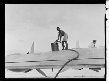 Tasman Empire Airways flying boat, RMA New Zealand ZK-AME at Lauthala Bay Suva, Fiji, includes captain in uniform and unidentified Fijian man refuelling aircraft