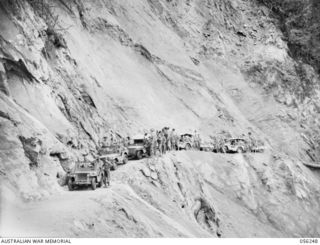 REINHOLD HIGHWAY, NEW GUINEA. 1943-08-25. CONVOY FROM HEADQUARTERS, ROYAL AUSTRALIAN ENGINEERS, 11TH AUSTRALIAN DIVISION ON THE BENCHING OF A ROCK FACE IN THE ELOA BASIN AREA, WHILE THE ROAD ..