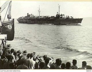 ORO BAY, NEW GUINEA. 1945-03-30. HEADQUARTERS 26 INFANTRY BRIGADE TROOPS ABOARD THE VAN HEUTSZ IN THE FOREGROUND IS PASSED BY P149, A LARGER TROOPSHIP DURING MOVEMENT TO MILNE BAY. MEN SHOUT TO ..