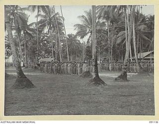 JACQUINOT BAY, NEW BRITAIN. 1945-04-21. HEADQUARTERS 5 DIVISION TROOPS ATTENDING A SIMPLE BUT IMPRESSIVE CEREMONY ON ANZAC DAY TO PAY HOMAGE TO THE FALLEN OF 1914-1918