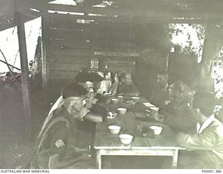 NEW IRELAND, 1945-10. ALLIED AND JAPANESE SERVICE PERSONNEL HOLDING A DISCUSSION IN A HUT. (RNZAF OFFICIAL PHOTOGRAPH.)