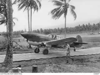 MILNE BAY, PAPUA. 1942-09. SQUADRON LEADER K.W. TRUSCOTT, COMMANDING OFFICER OF 76 SQUADRON RAAF, RETURNS FROM AN OPERATIONAL FLIGHT AND TAXIS UP THE METAL RUNWAY TO THE DISPERSAL BAYS SET IN AMONG ..