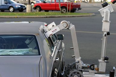 A Remote Operated Neutralization System uses a robotic arm to remove a simulated bomb out of the back seat of a car during training at the Marine Corps Base Hawaii, Hawaii, Post Exchange parking lot on Dec. 9, 2004.(U.S. Marine Corps official photo by CPL. Nicholas Riddle) (Released)