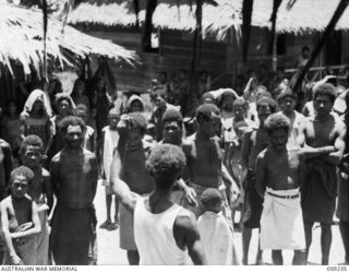 HOPOI, NEW GUINEA, 1943-10-20. A NATIVE INTERPRETER TRANSLATING THE ADDRESS OF NX155085 CAPTAIN R.G. ORMSBY OF THE AUSTRALIAN AND NEW GUINEA ADMINISTRATIVE UNIT TO THE NATIVE VILLAGERS