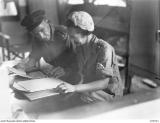 VFX38757 Sister J Rogers, Australian Army Nursing Service (left), with SX9912 Chaplain V F Meyer (right) going through a list of patients at the 2/1st General Hospital to determine those of the ..