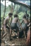 Young men singeing off a pig hair