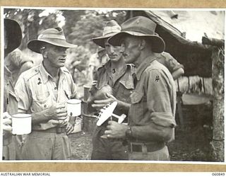 NEW GUINEA. 1943-11-20. MEMBERS OF THE 18TH AUSTRALIAN INFANTRY BRIGADE STUDYING A DECORATIVE ASH TRAY MADE BY PRIVATE HAWKINS. SEEN ARE LEFT TO RIGHT: VX82344 PRIVATE C. M. PHILLIPS, 2/12TH ..
