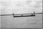 Canoes: men use poles to move outrigger canoe
