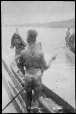 Back view of a man standing in a canoe paddling, Ramu River, New Guinea, 1935 / Sarah Chinnery