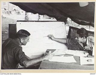 MALMAL VILLAGE, JACQUINOT BAY, NEW BRITAIN. 1945-07-18. CAPTAIN A. CAMPBELL, A COMMANDO OFFICER ON TIMOR (WHO WAS ALSO A WELL KNOWN WEST AUSTRALIAN FOOTBALLER) (1), WITH CORPORAL S.A. ROBINSON, ..